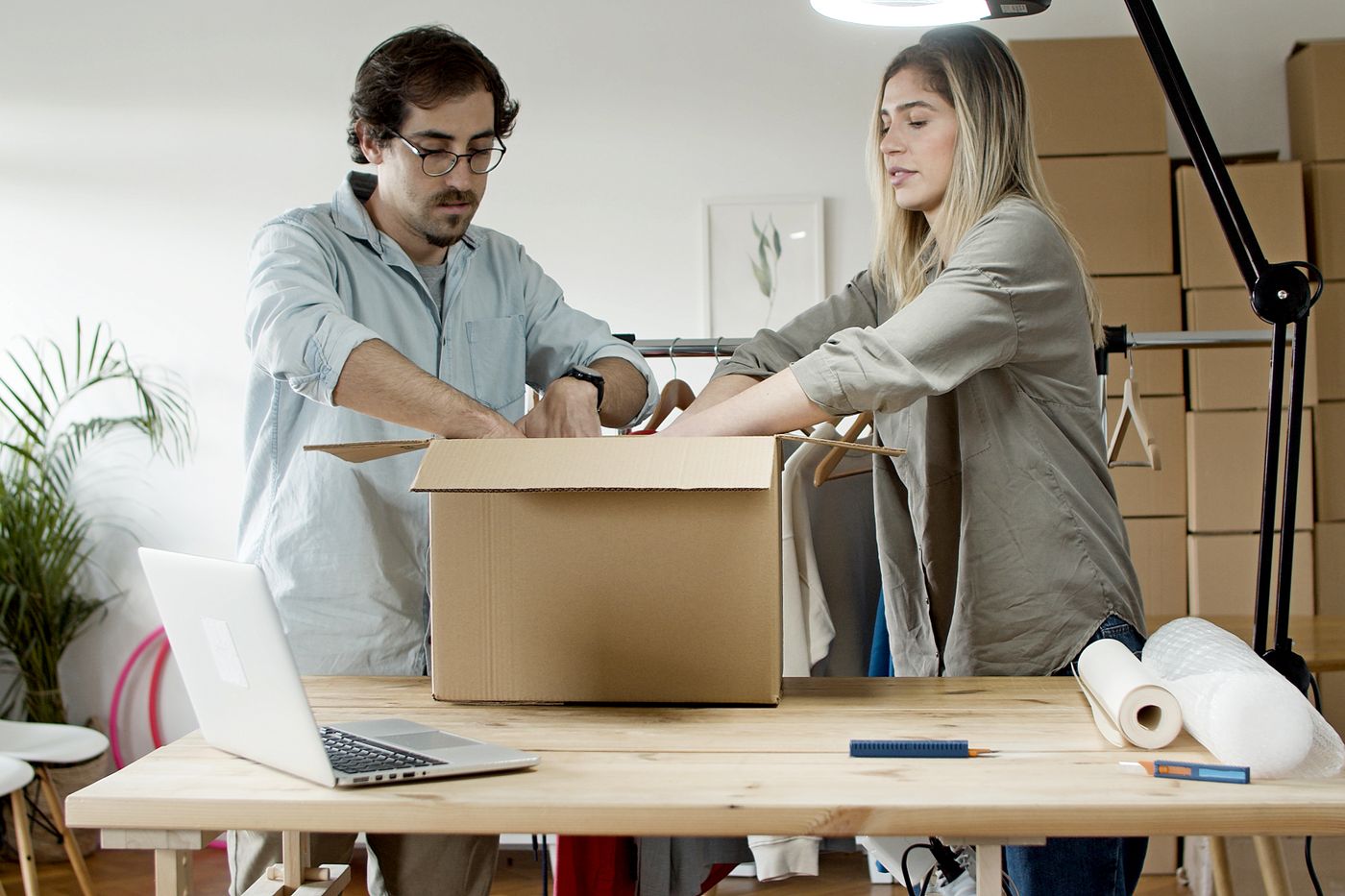 Two business owners packing clothing orders together in their studio